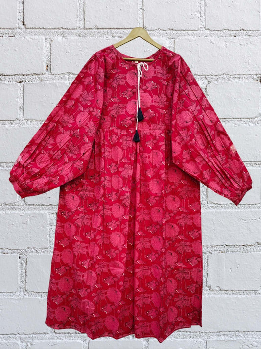 Crimson Floral Tassel Midi Dress — Puff Sleeves with gathered waist, displayed on a hanger against a textured wall.